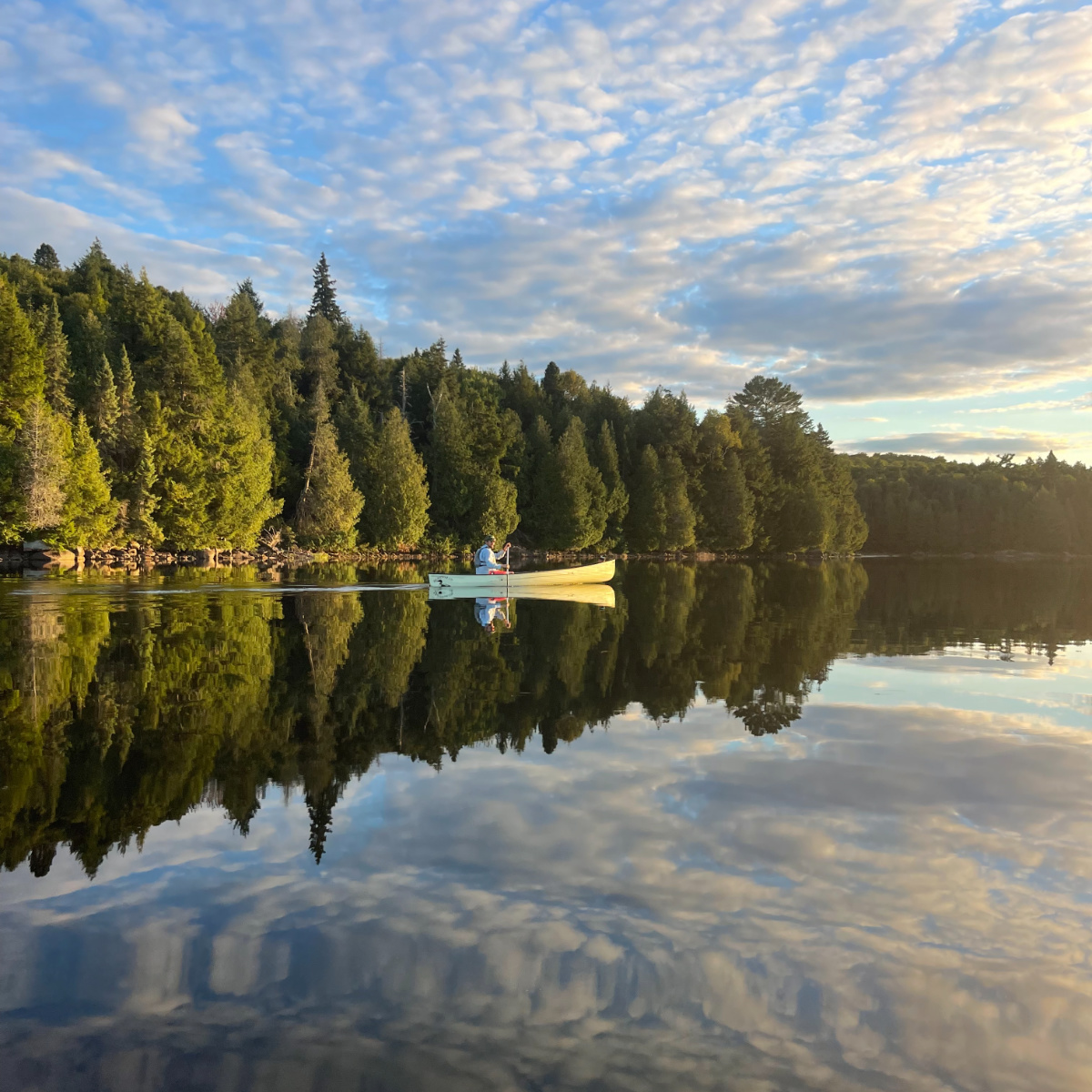 Canoeing through glassy water at sunset in Algonquin Park.